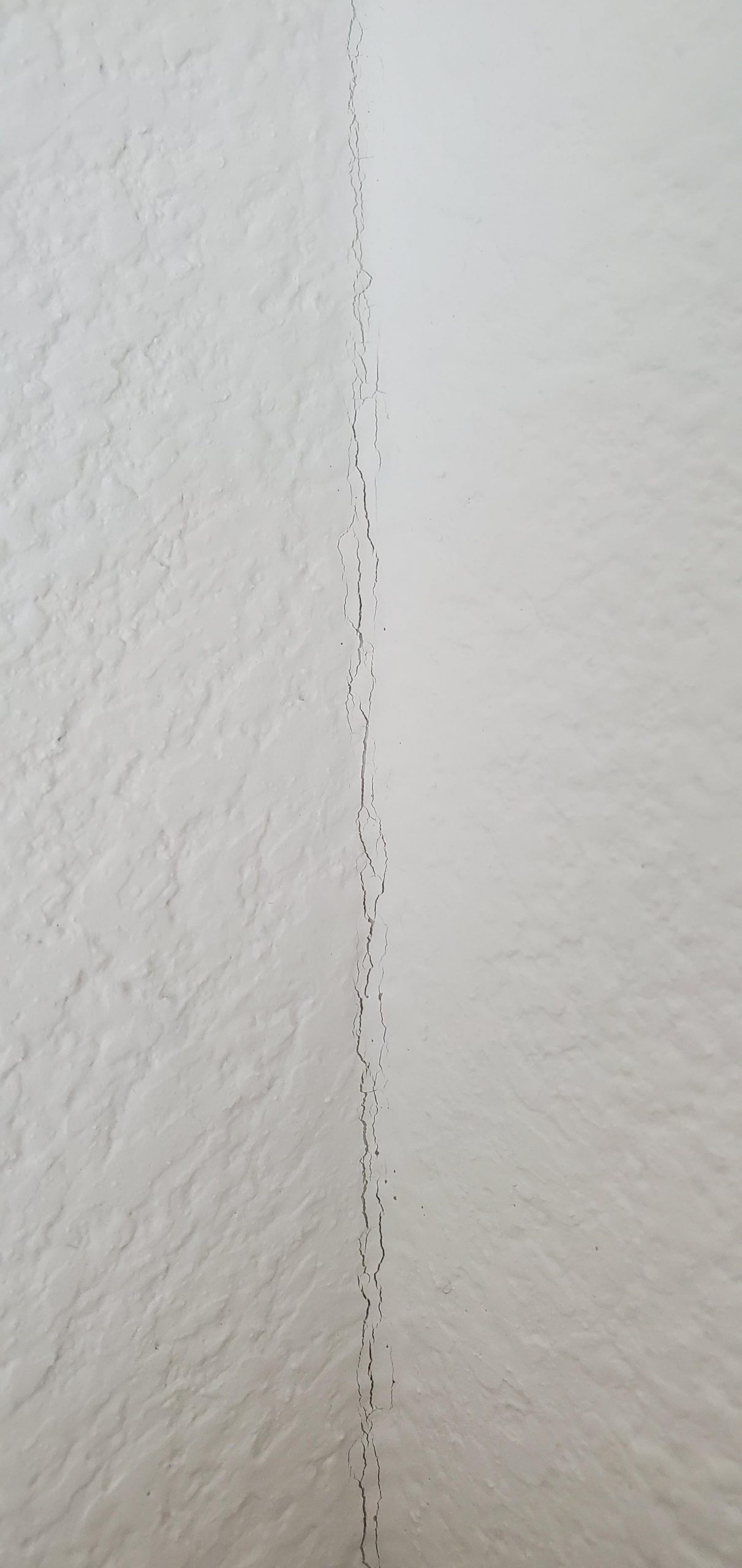 How do I repair these small cracks found in the corners of the walls throughout my entire new