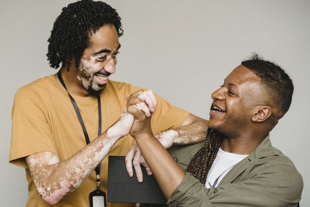 Laughing black male colleagues clasping hands in excitement together, hr management