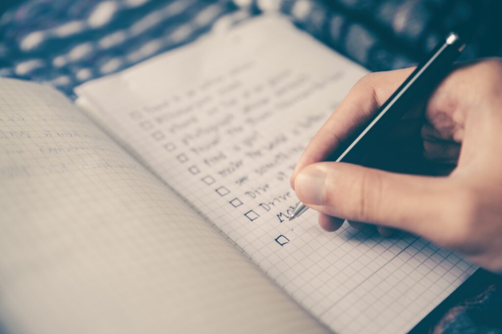 person writing bucket list on book productivity tips