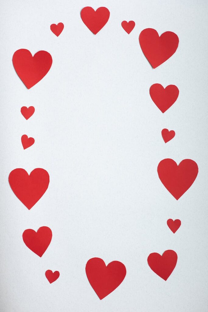 Top view paper cutout of different red hearts arranged in shape of oval on white background during saint valentine day - DIY Artwork Ideas
