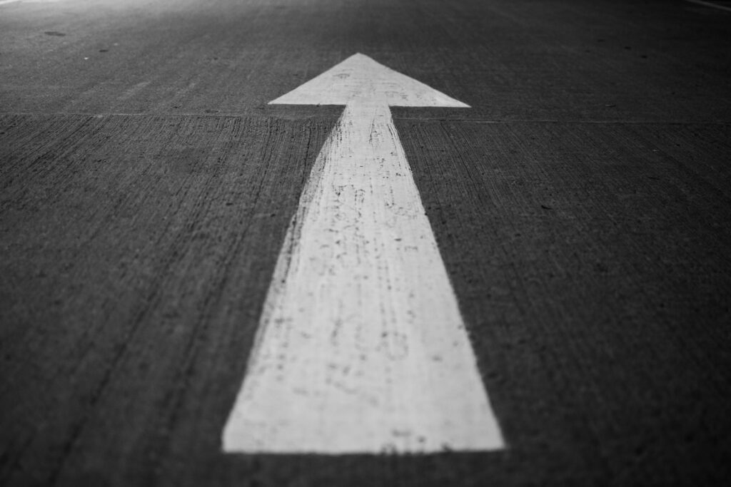 a black and white photo of an arrow painted on a road - Entrepreneurship and moving forward