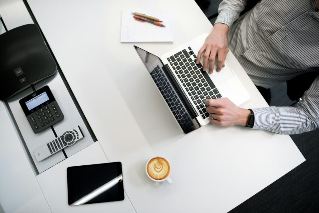 person using laptop on white wooden table - small business bookkeeping